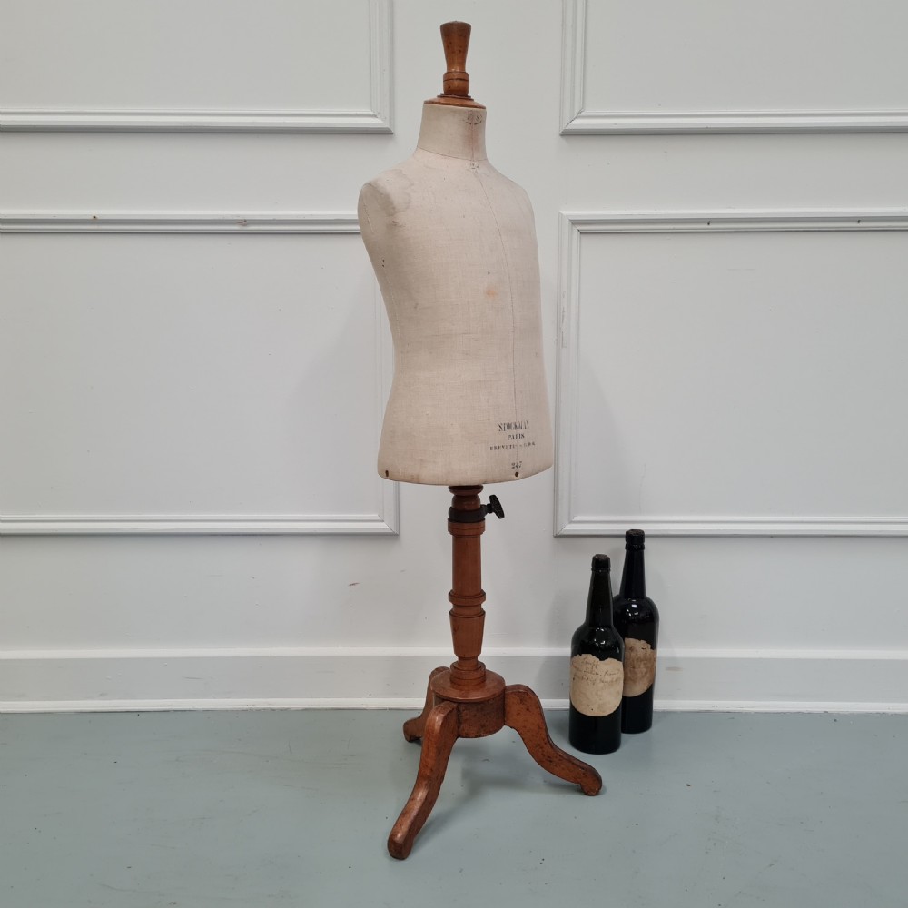 An antique French child-sized tailor mannequin by Stockman featuring a beige linen torso mounted on a turned wooden tripod stand. View VI