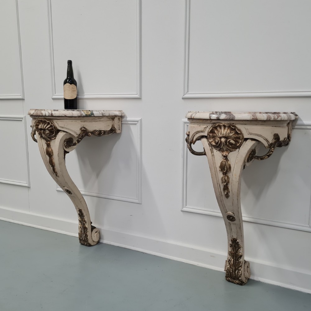 A pair of French nineteenth-century wall-mounted console tables with shaped marble tops and carved gilded single support legs. View III