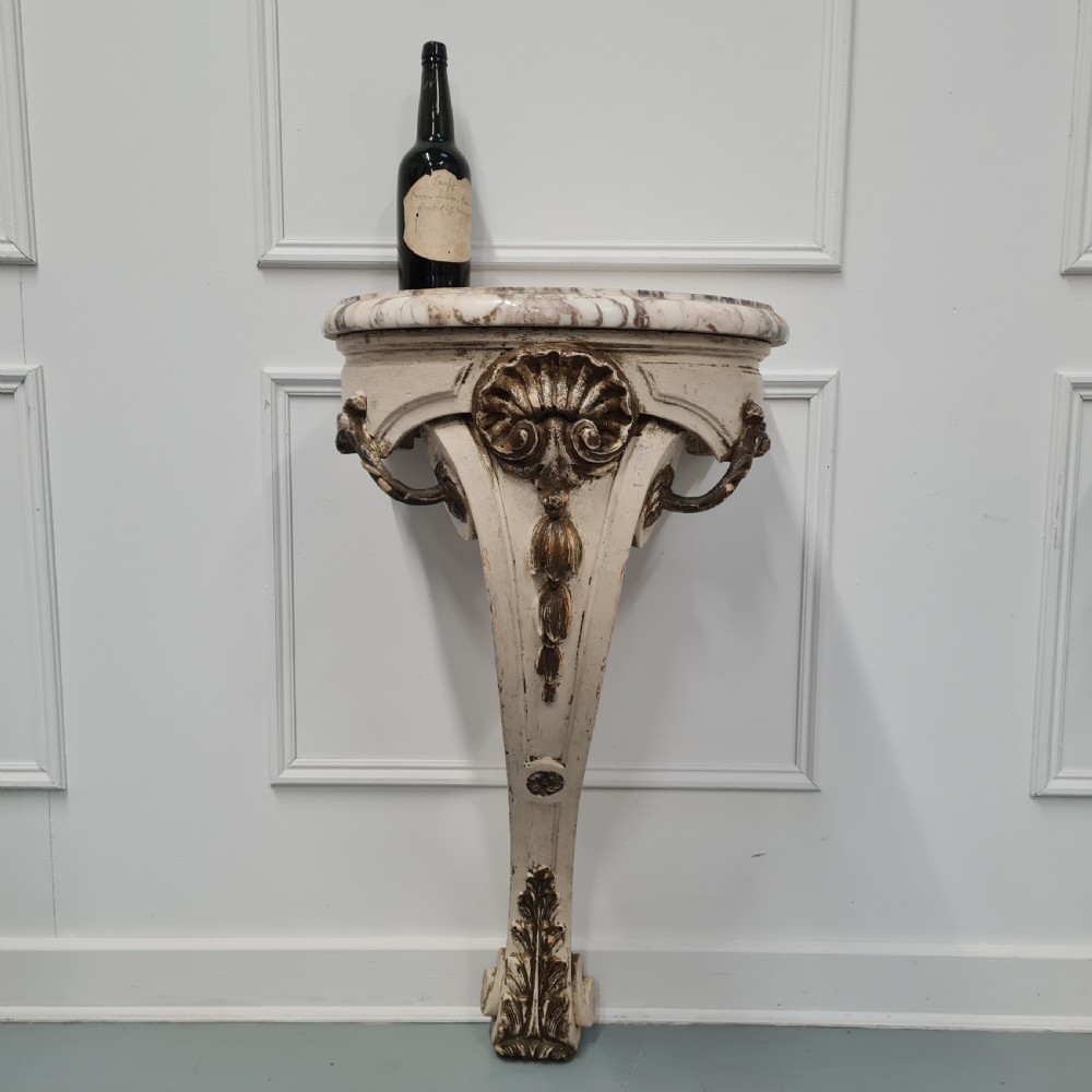 A pair of French nineteenth-century wall-mounted console tables with shaped marble tops and carved gilded single support legs. View V