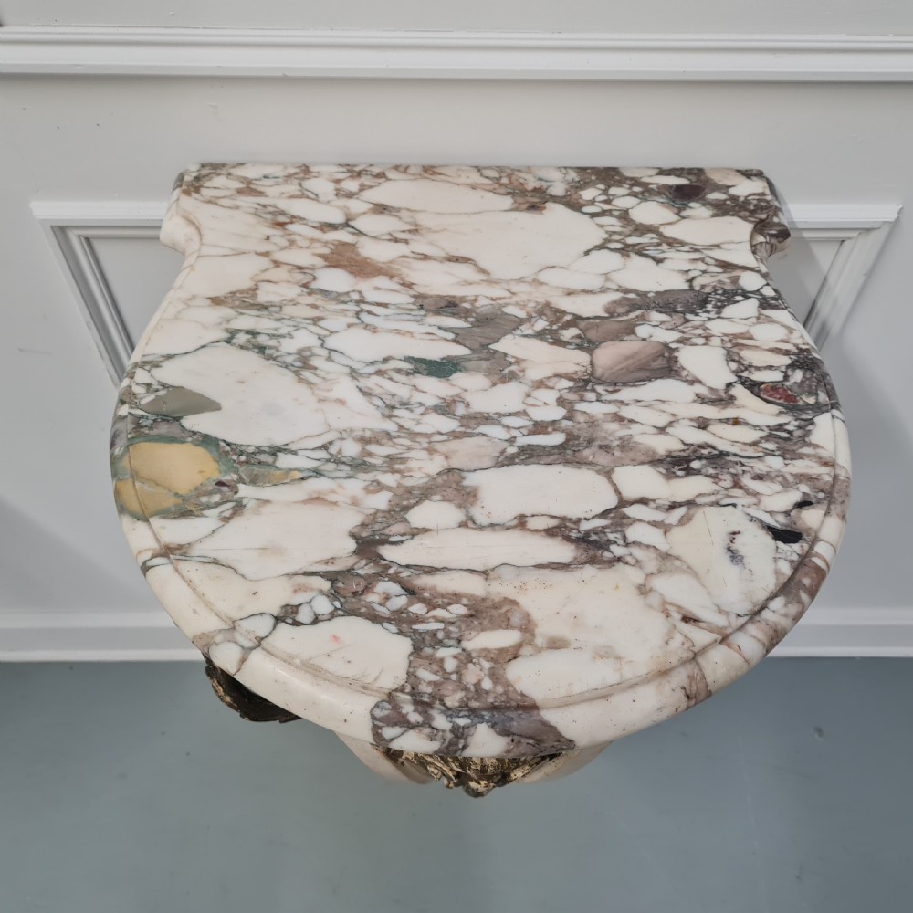 A pair of French nineteenth-century wall-mounted console tables with shaped marble tops and carved gilded single support legs. View VI