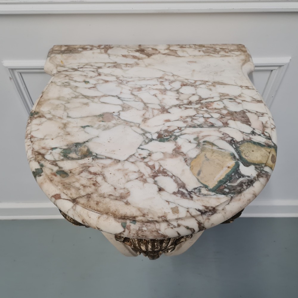 A pair of French nineteenth-century wall-mounted console tables with shaped marble tops and carved gilded single support legs. View VII