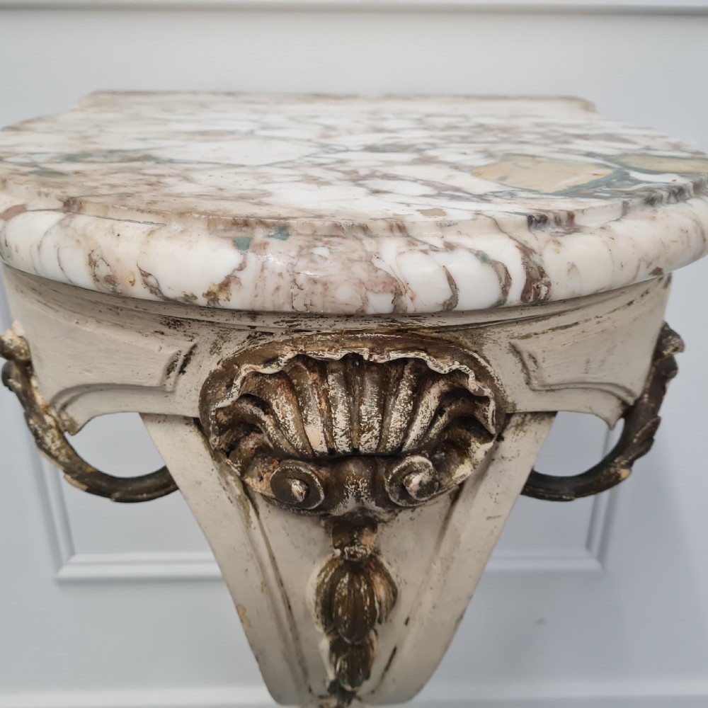 A pair of French nineteenth-century wall-mounted console tables with shaped marble tops and carved gilded single support legs. View VIII