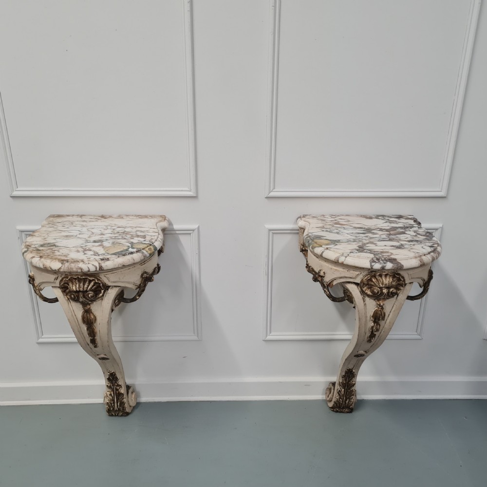 A pair of French nineteenth-century wall-mounted console tables with shaped marble tops and carved gilded single support legs. View X