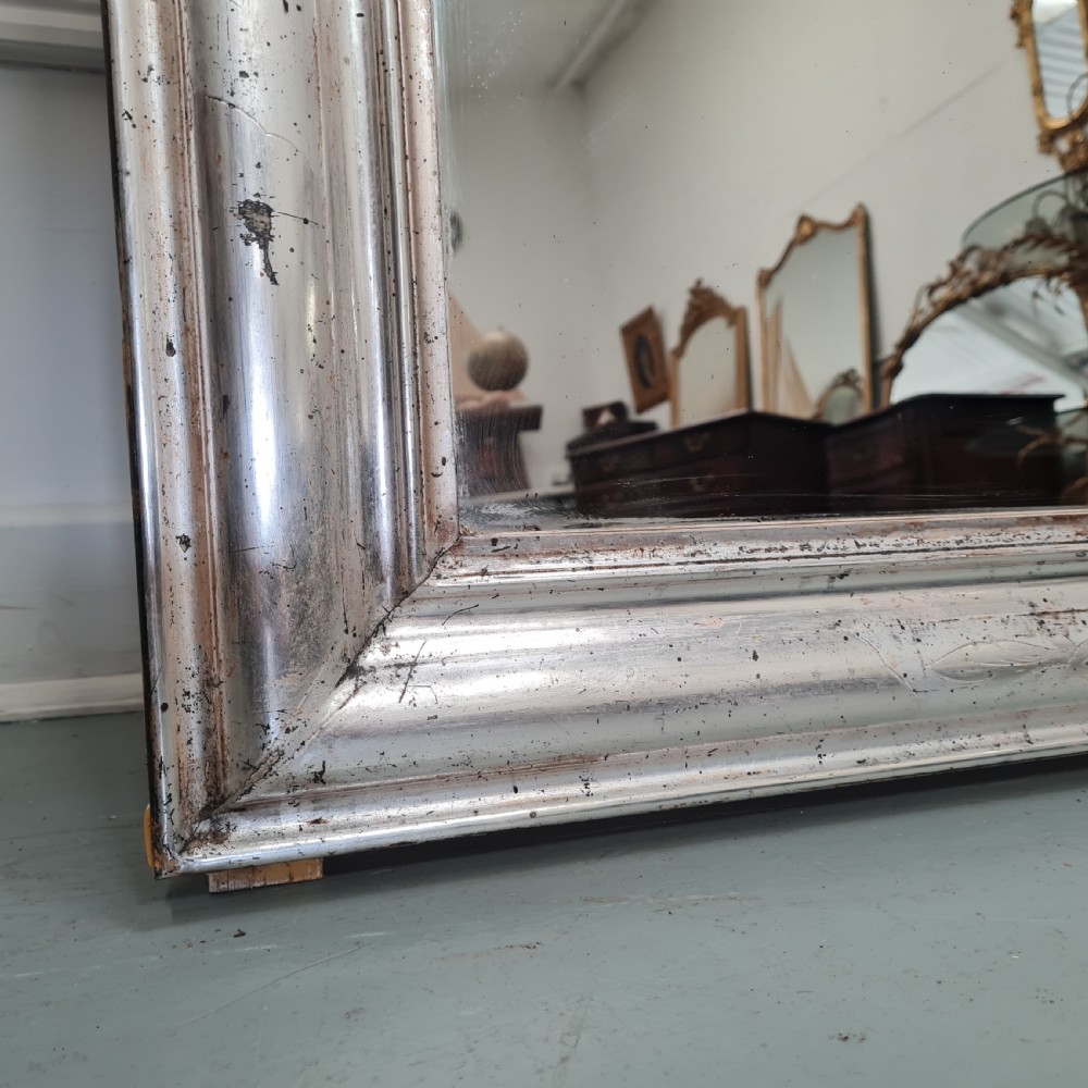A large 19th-century rectangular French mirror featuring a silver gilded frame crowned with a carved gold Rococo shell cresting. View II