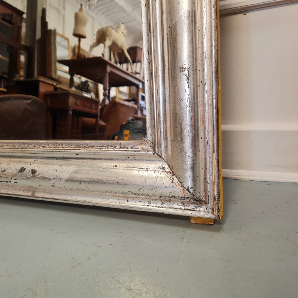 A large 19th-century rectangular French mirror featuring a silver gilded frame crowned with a carved gold Rococo shell cresting. View IV