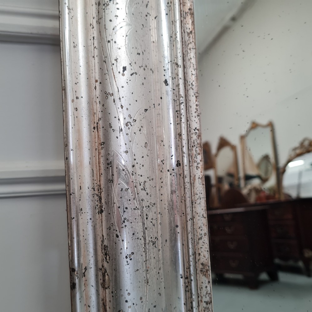 A large 19th-century rectangular French mirror featuring a silver gilded frame crowned with a carved gold Rococo shell cresting. View V