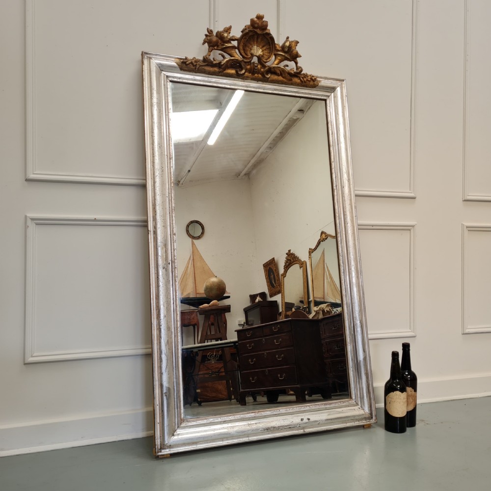 A large 19th-century rectangular French mirror featuring a silver gilded frame crowned with a carved gold Rococo shell cresting. View VI