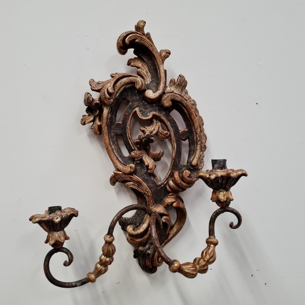 A pair of carved wood wall sconces featuring ornate scrollwork, aged silver leaf finish, and twin candle arms. View III