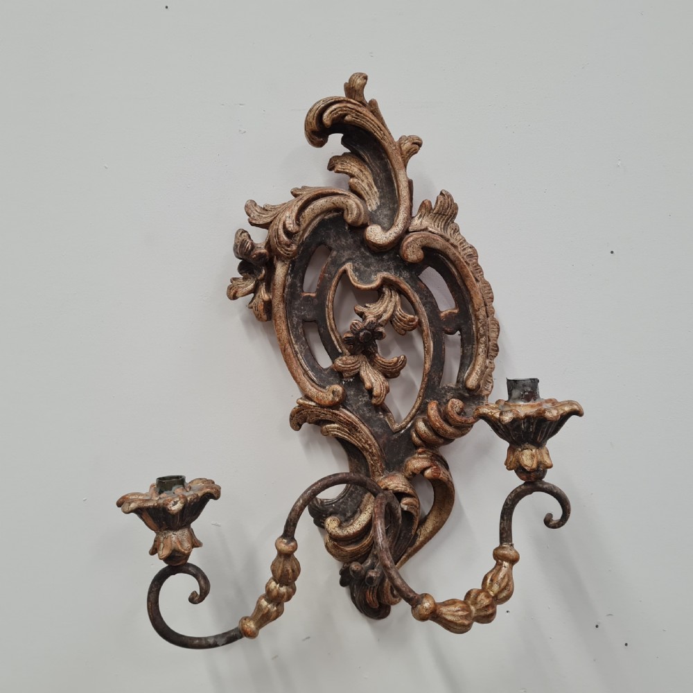 A pair of carved wood wall sconces featuring ornate scrollwork, aged silver leaf finish, and twin candle arms. View IV
