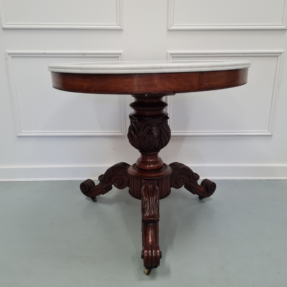 A 19th-century French gueridon table featuring a circular white marble top supported by a carved dark mahogany pedestal and scrolled tripod base.