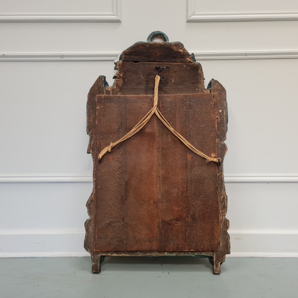 An 18th-century French gilded wooden mirror featuring a carved ornate crest with bow and garland motifs set against a blue background, enclosing a foxed rectangular mirror plate. View VIII