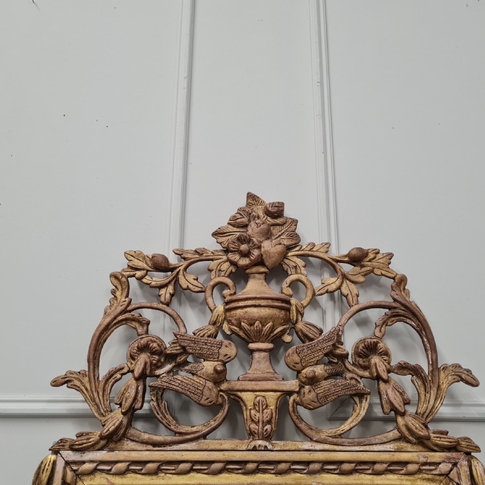 A large antique French giltwood marriage mirror circa 1900 featuring an elaborate carved crest with an urn and bird motifs above a rectangular beaded frame. View III