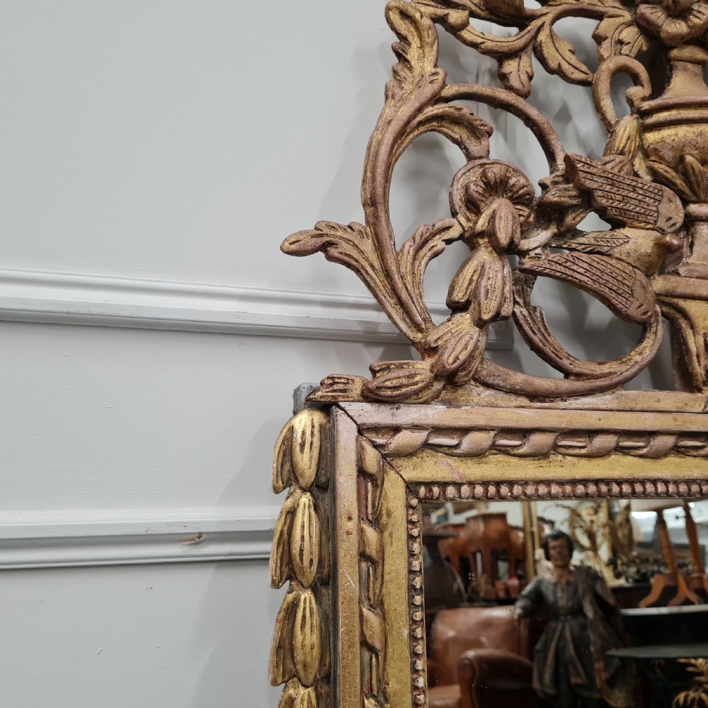 A large antique French giltwood marriage mirror circa 1900 featuring an elaborate carved crest with an urn and bird motifs above a rectangular beaded frame. View IV