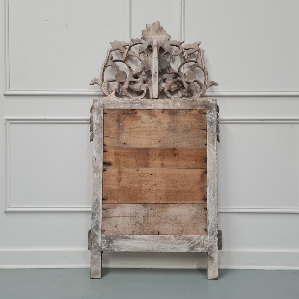 A large antique French giltwood marriage mirror circa 1900 featuring an elaborate carved crest with an urn and bird motifs above a rectangular beaded frame. View VII
