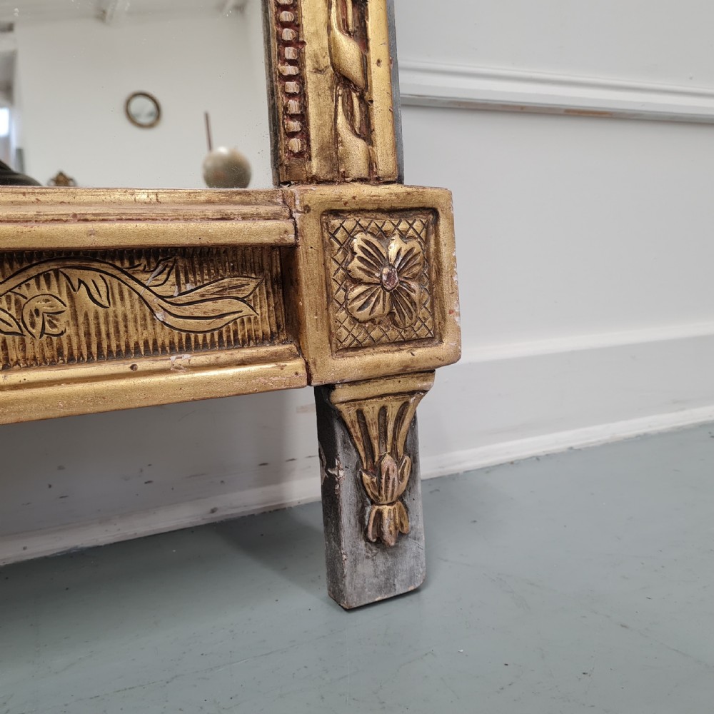 A large antique French giltwood marriage mirror circa 1900 featuring an elaborate carved crest with an urn and bird motifs above a rectangular beaded frame. View VIII