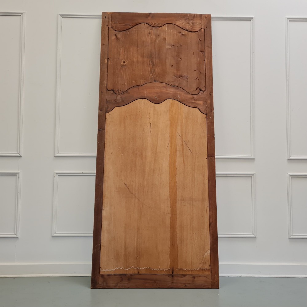 A tall French trumeau mirror featuring a cream painted frame with gilt carved moulding, an upper relief panel displaying a trophy motif, and rectangular glass below. View IV