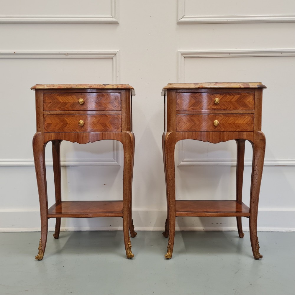 A pair of French 1930s serpentine bedside tables featuring marble tops, chevron veneer drawers, cabriole legs with brass mounts, and a lower shelf.