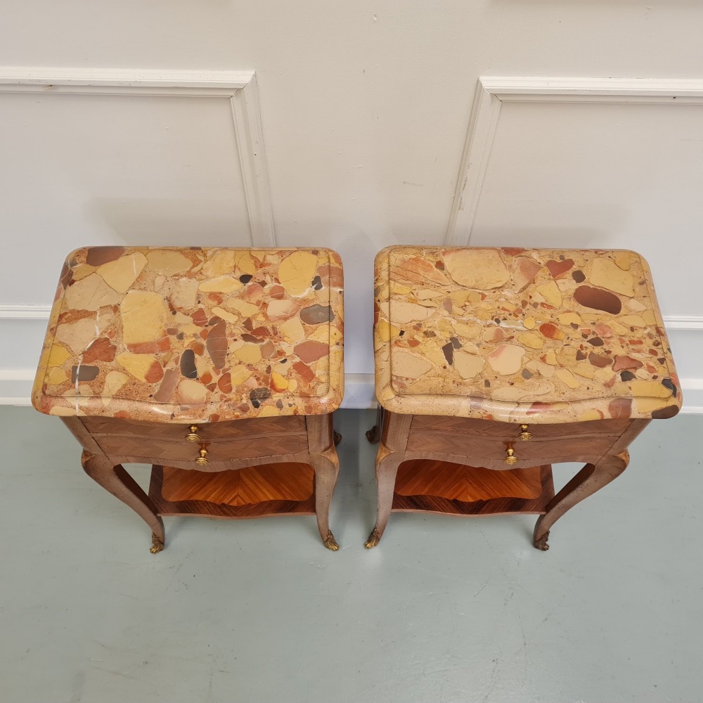 A pair of French 1930s serpentine bedside tables featuring marble tops, chevron veneer drawers, cabriole legs with brass mounts, and a lower shelf. View II
