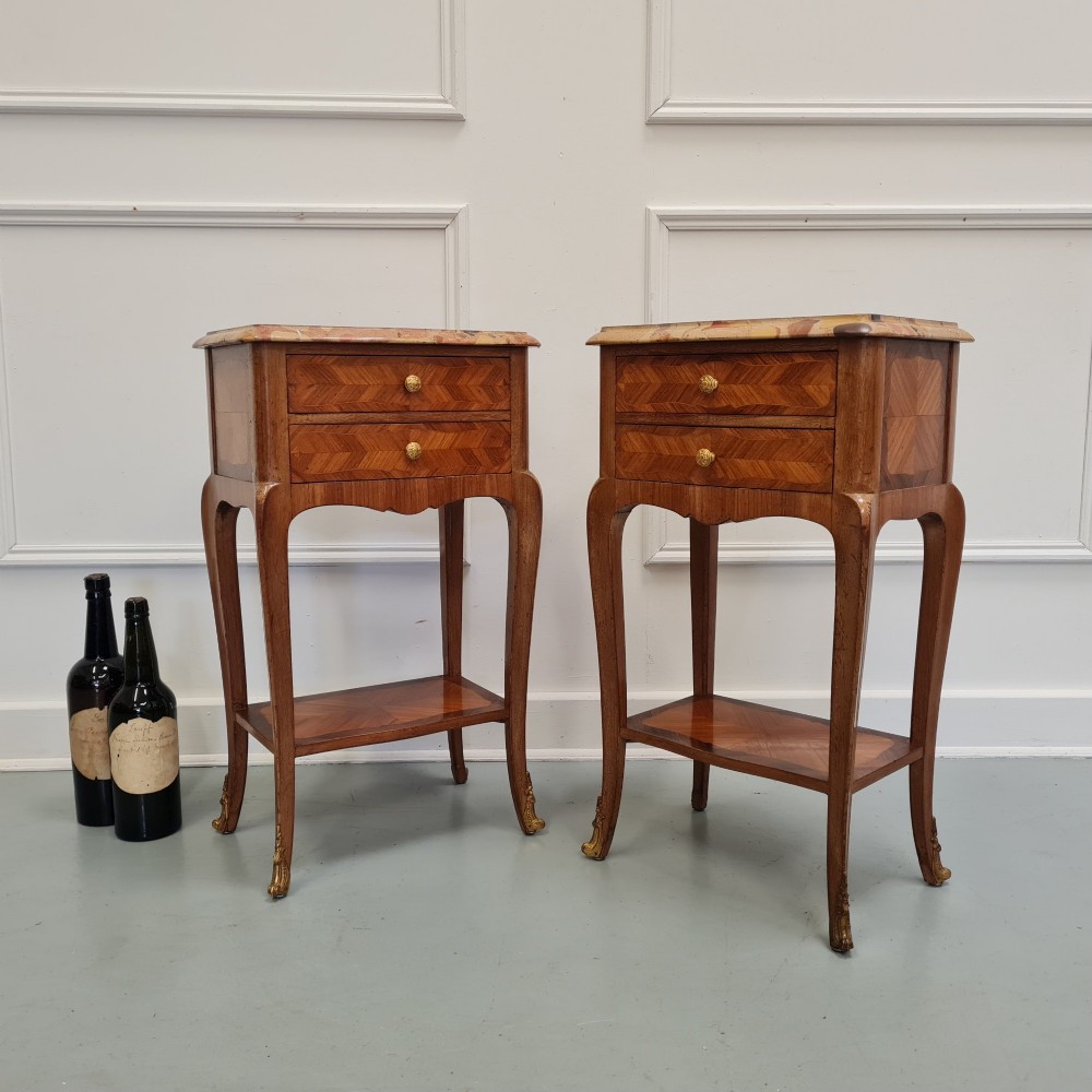 A pair of French 1930s serpentine bedside tables featuring marble tops, chevron veneer drawers, cabriole legs with brass mounts, and a lower shelf. View IV