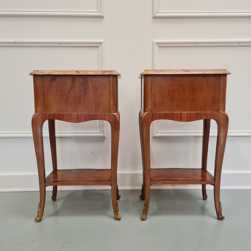 A pair of French 1930s serpentine bedside tables featuring marble tops, chevron veneer drawers, cabriole legs with brass mounts, and a lower shelf. View VI