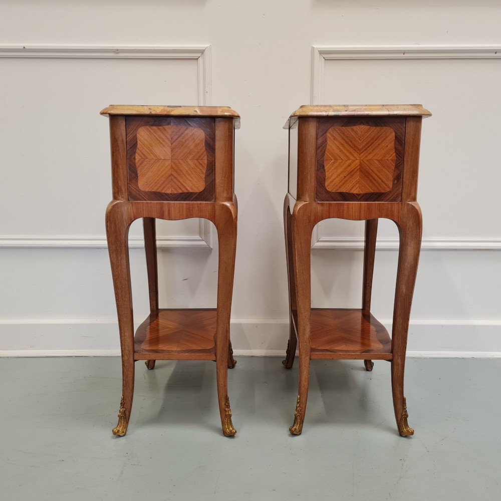 A pair of French 1930s serpentine bedside tables featuring marble tops, chevron veneer drawers, cabriole legs with brass mounts, and a lower shelf. View VII