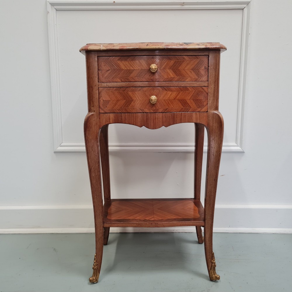A pair of French 1930s serpentine bedside tables featuring marble tops, chevron veneer drawers, cabriole legs with brass mounts, and a lower shelf. View VIII