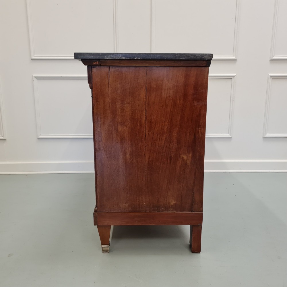 A French Empire mahogany commode featuring three wide drawers with brass handles, central keyhole escutcheons, and a dark marble top. View VIII