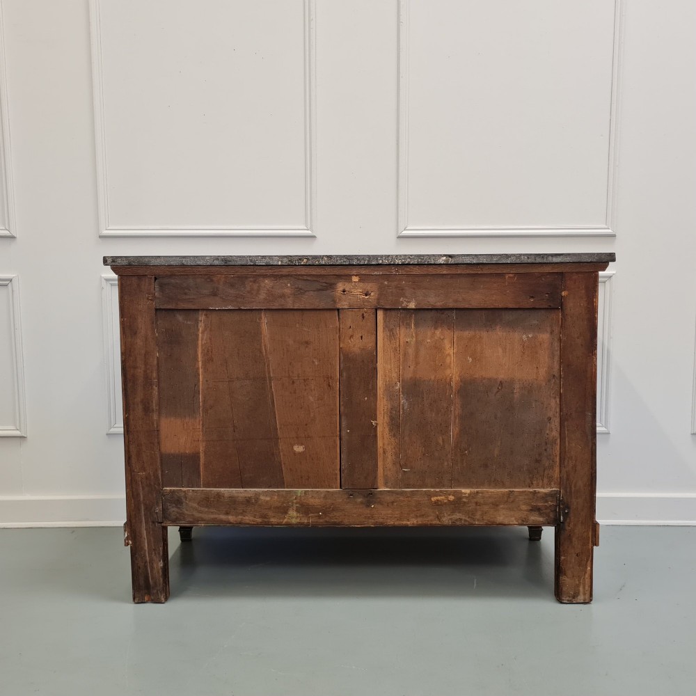 A French Empire mahogany commode featuring three wide drawers with brass handles, central keyhole escutcheons, and a dark marble top. View IX