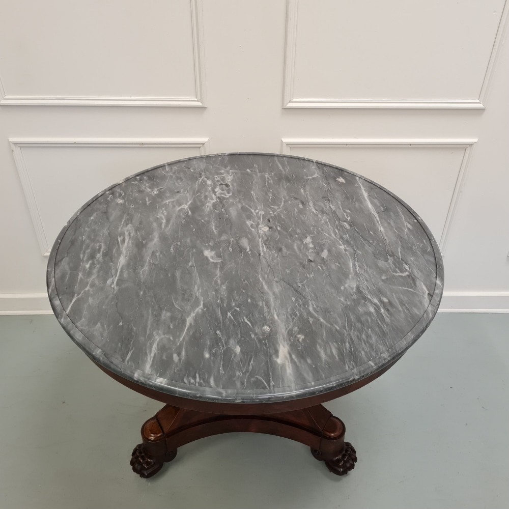 A 19th-century French gueridon featuring a circular dark grey marble top set upon a flame mahogany pedestal with a triform base and carved paw feet. View II