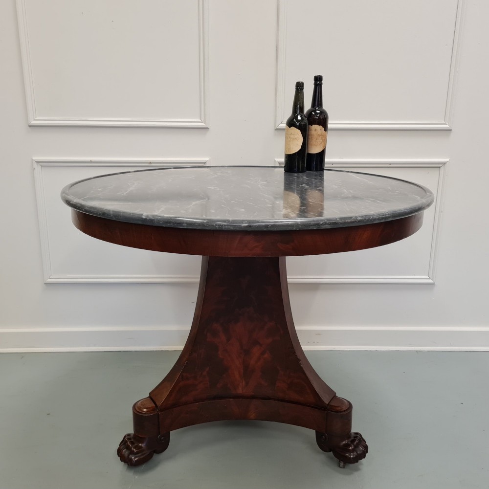 A 19th-century French gueridon featuring a circular dark grey marble top set upon a flame mahogany pedestal with a triform base and carved paw feet. View V