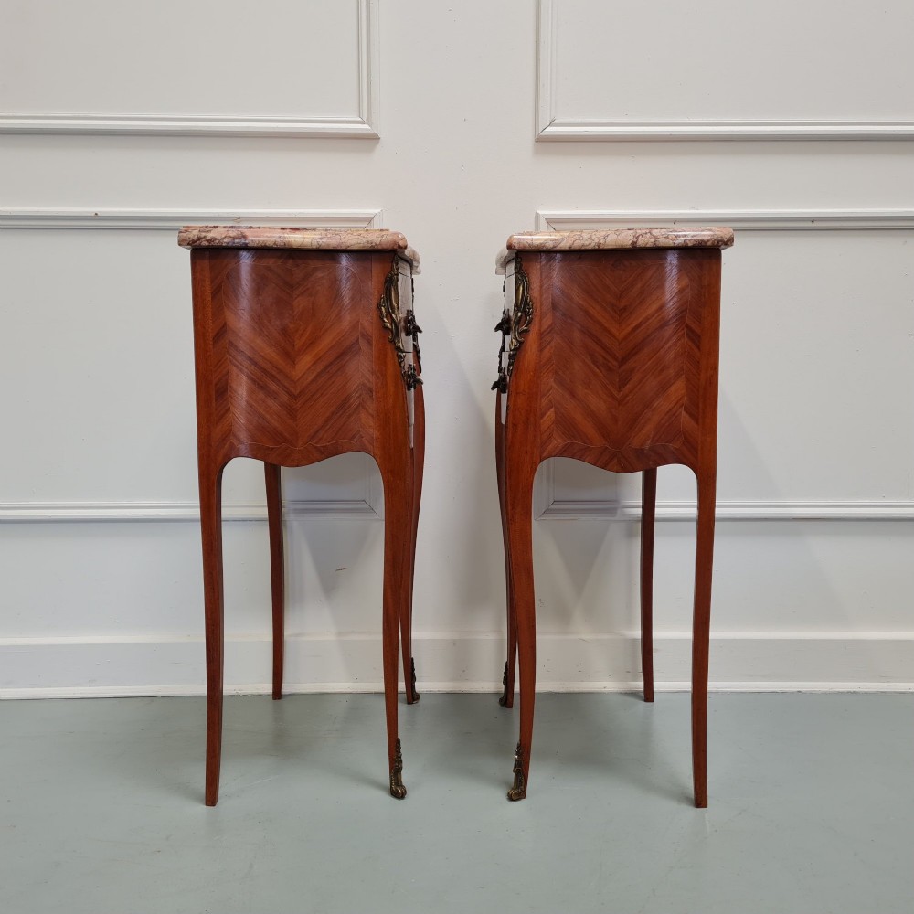 A pair of French 1930s bedside tables featuring variegated marble tops, walnut parquetry drawers, gilt brass mounts, and slender cabriole legs. View II