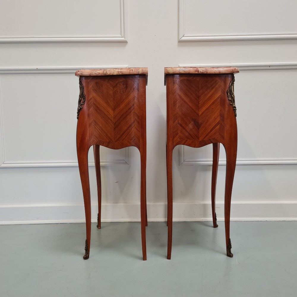 A pair of French 1930s bedside tables featuring variegated marble tops, walnut parquetry drawers, gilt brass mounts, and slender cabriole legs. View IV
