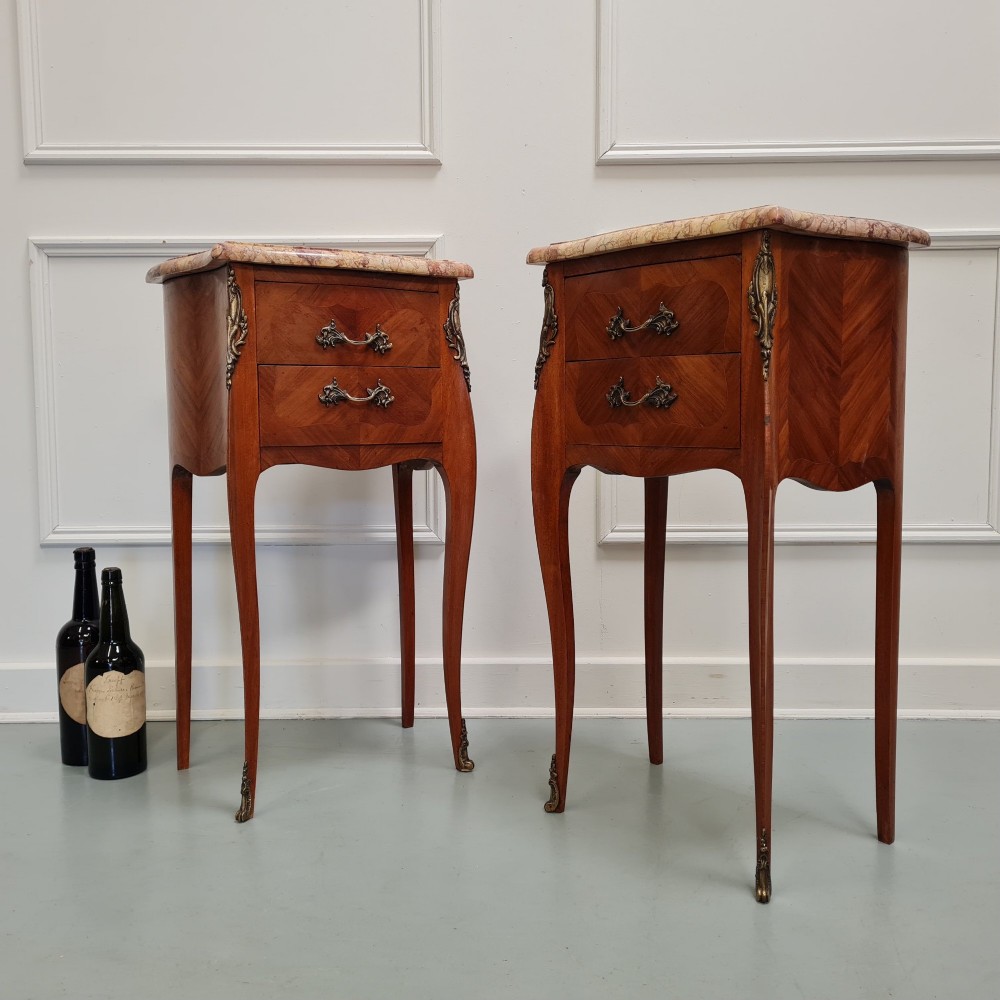 A pair of French 1930s bedside tables featuring variegated marble tops, walnut parquetry drawers, gilt brass mounts, and slender cabriole legs. View VII