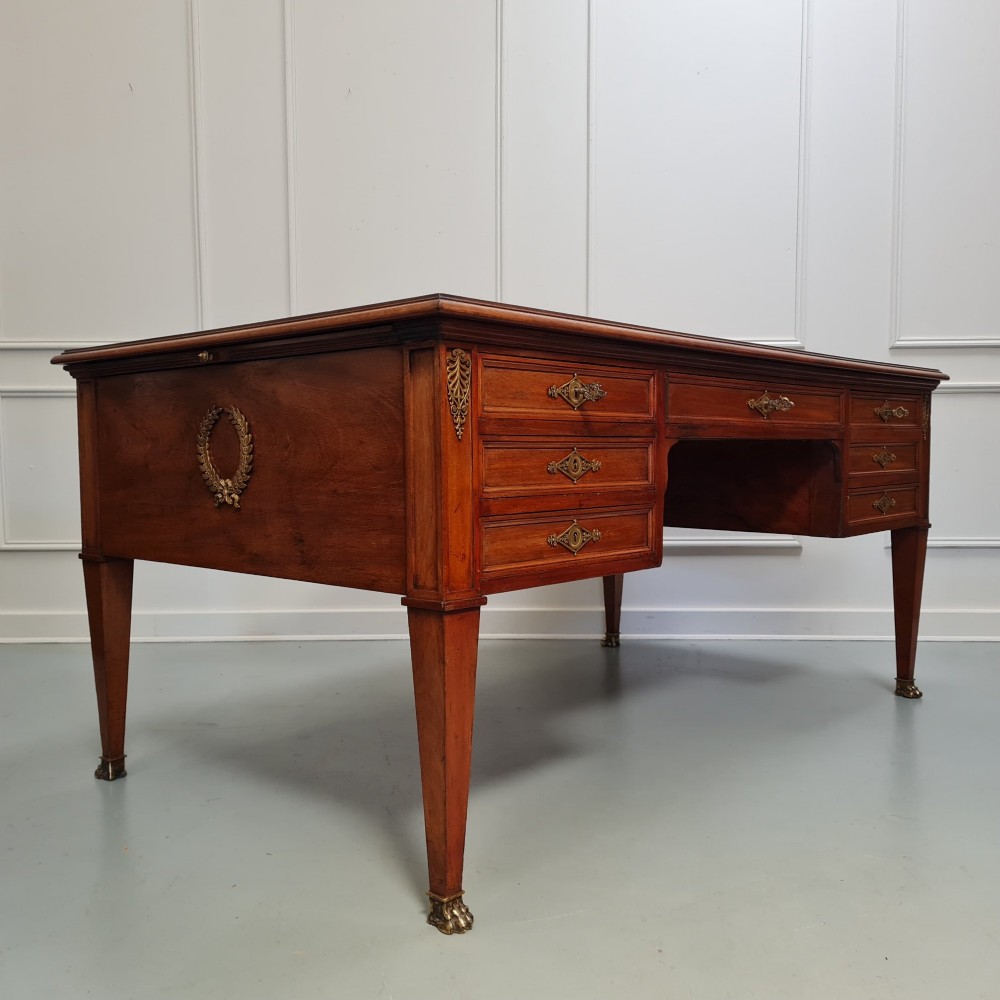 A large Empire style mahogany writing desk featuring a leather inset top, brass mounts, ornate escutcheons, and tapered square legs with brass feet. View II