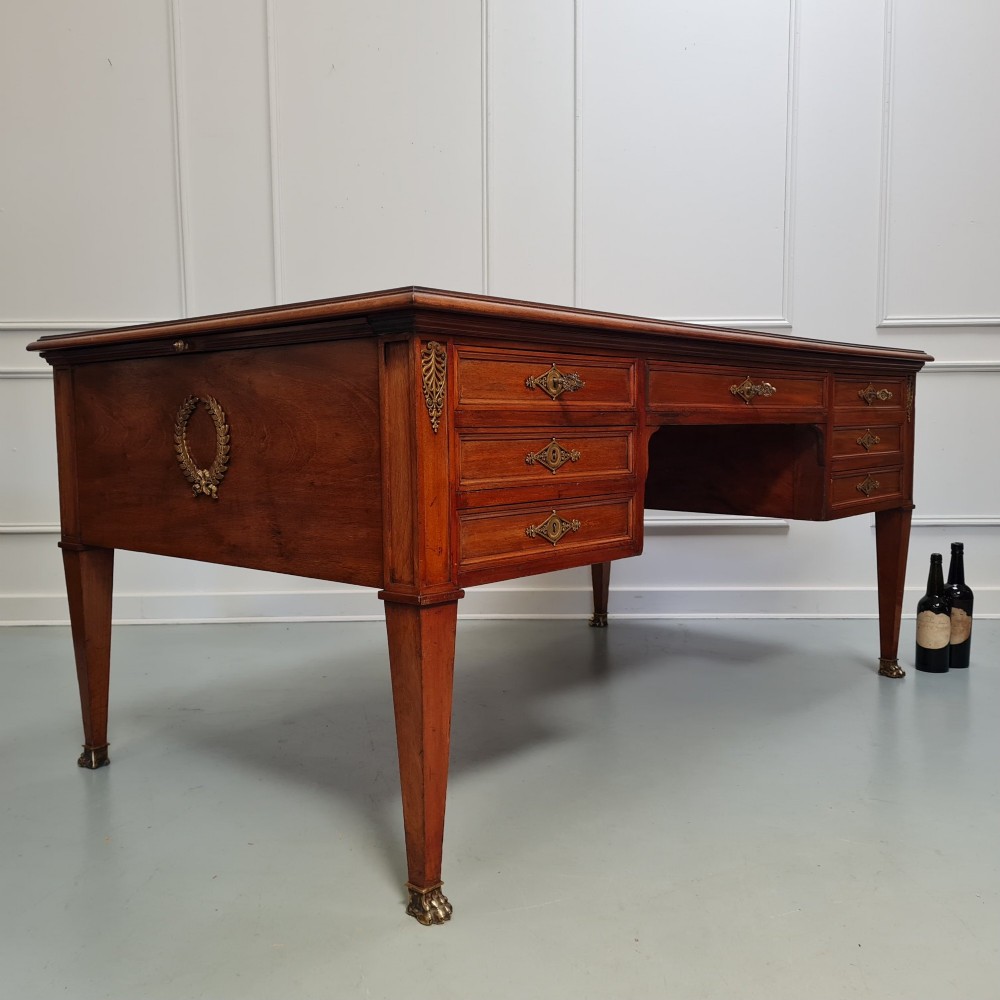 A large Empire style mahogany writing desk featuring a leather inset top, brass mounts, ornate escutcheons, and tapered square legs with brass feet. View III
