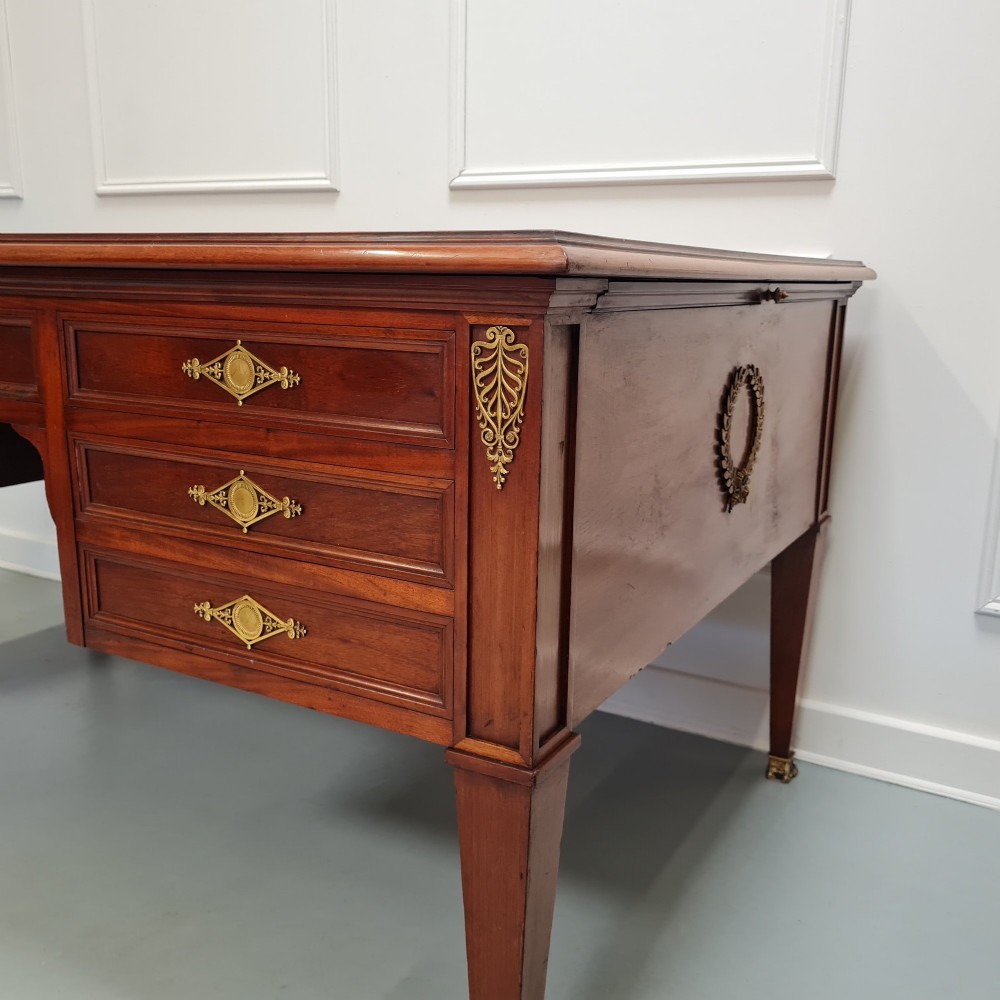 A large Empire style mahogany writing desk featuring a leather inset top, brass mounts, ornate escutcheons, and tapered square legs with brass feet. View VIII