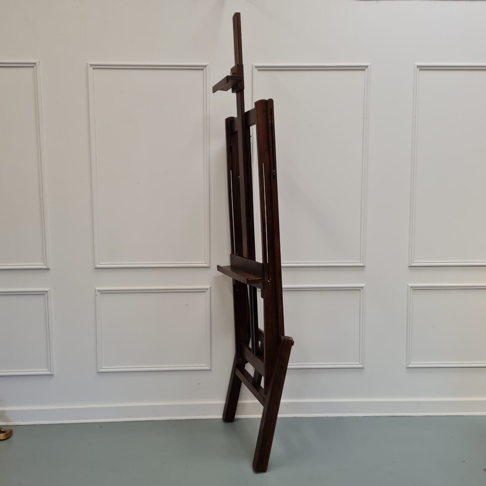 A dark brown French oak H-frame studio easel featuring an adjustable canvas shelf and metal side fixtures. View IV