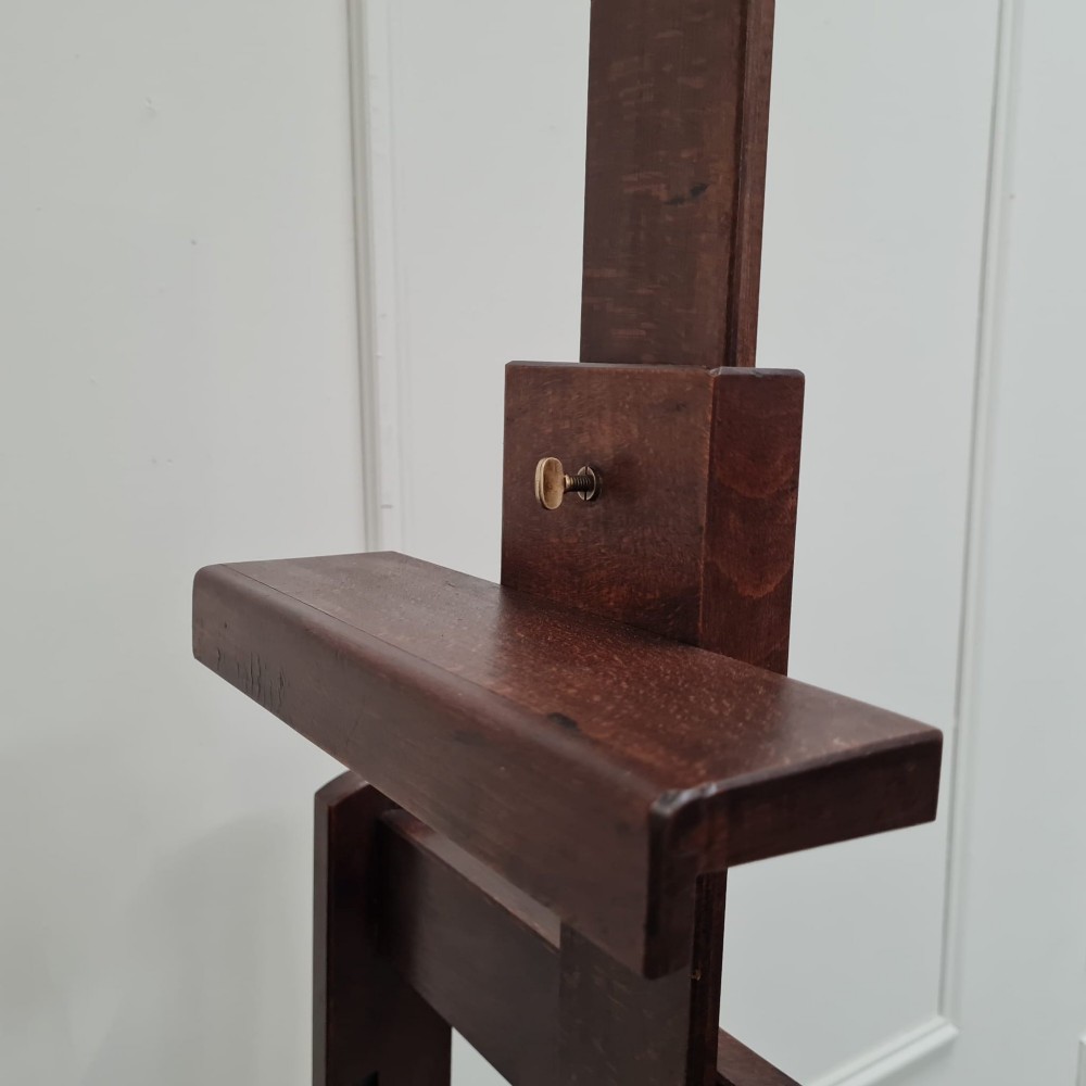 A dark brown French oak H-frame studio easel featuring an adjustable canvas shelf and metal side fixtures. View V