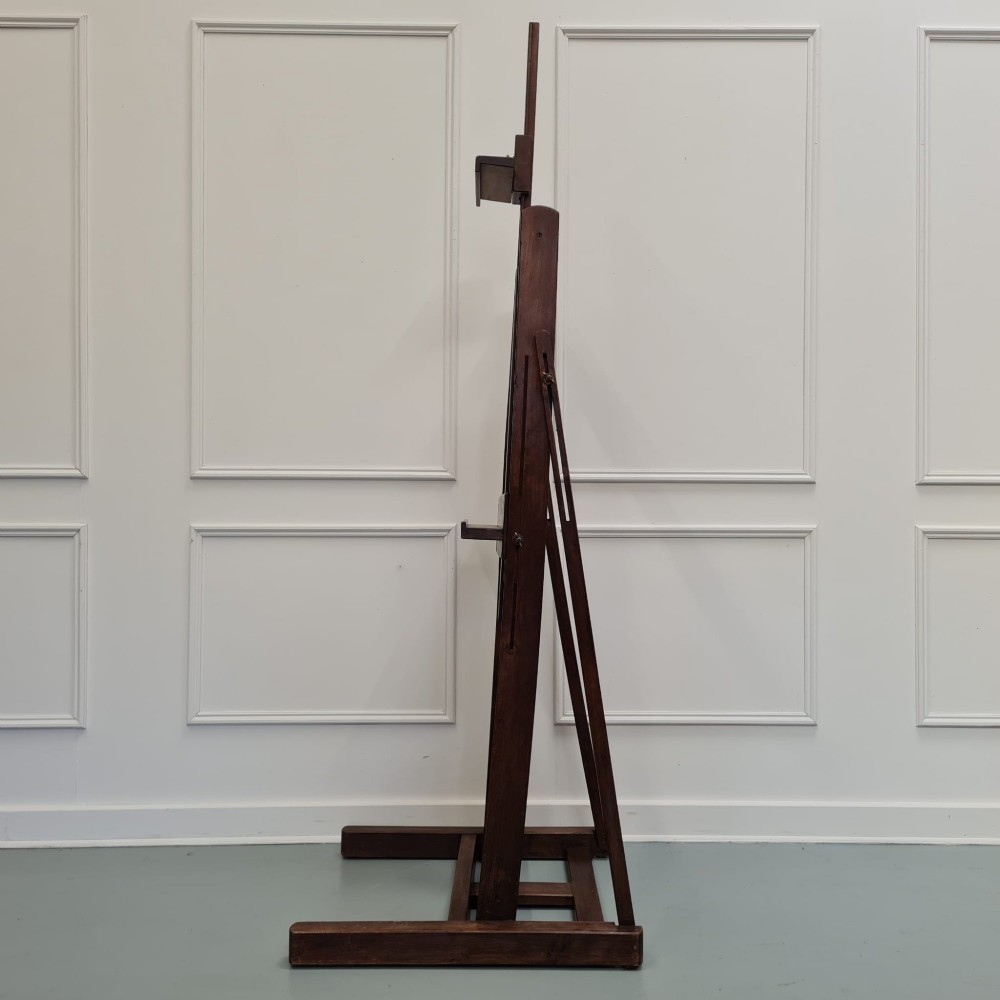 A dark brown French oak H-frame studio easel featuring an adjustable canvas shelf and metal side fixtures. View VII