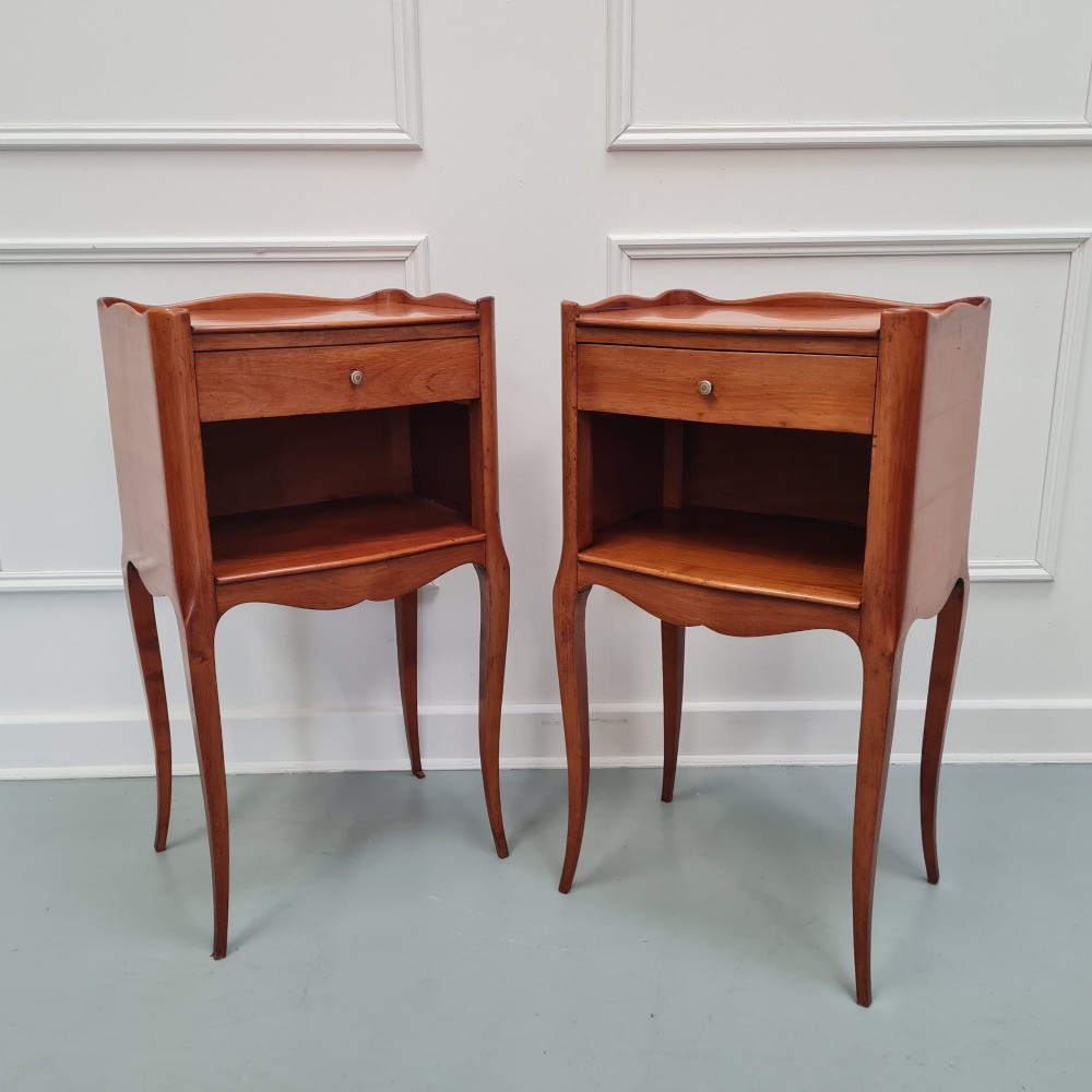 A pair of French cherry wood bedside tables featuring single drawers with small pull knobs, open lower shelves, and slender cabriole legs. View III