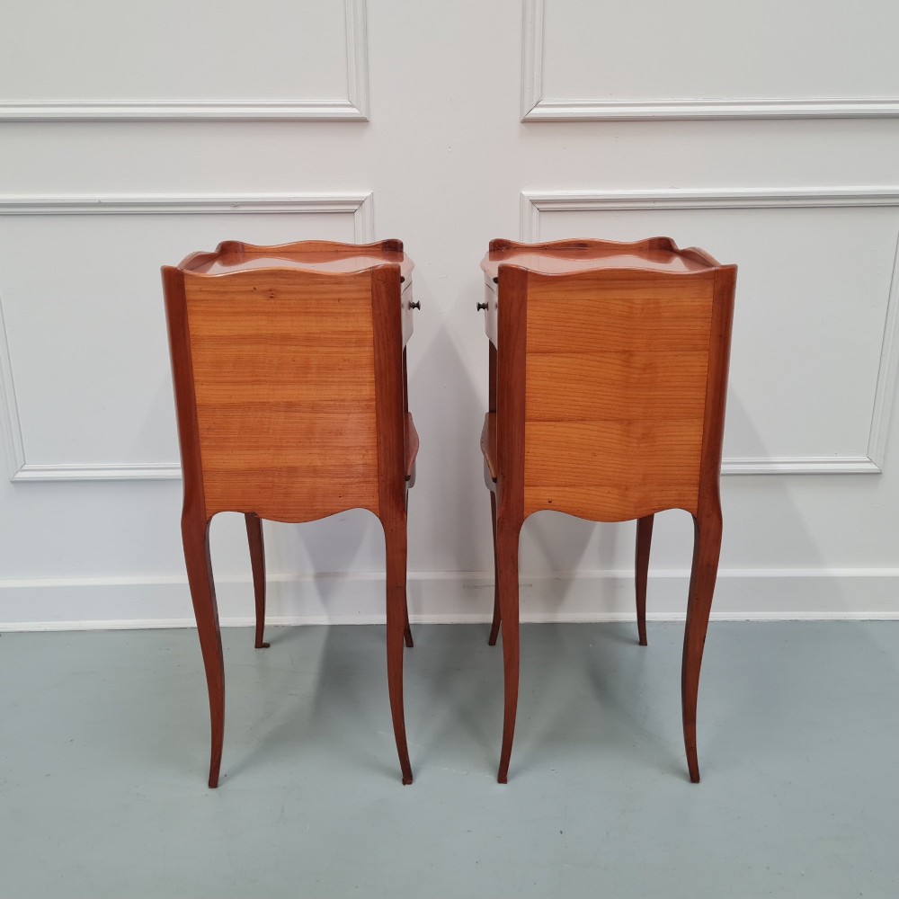 A pair of French cherry wood bedside tables featuring single drawers with small pull knobs, open lower shelves, and slender cabriole legs. View IV