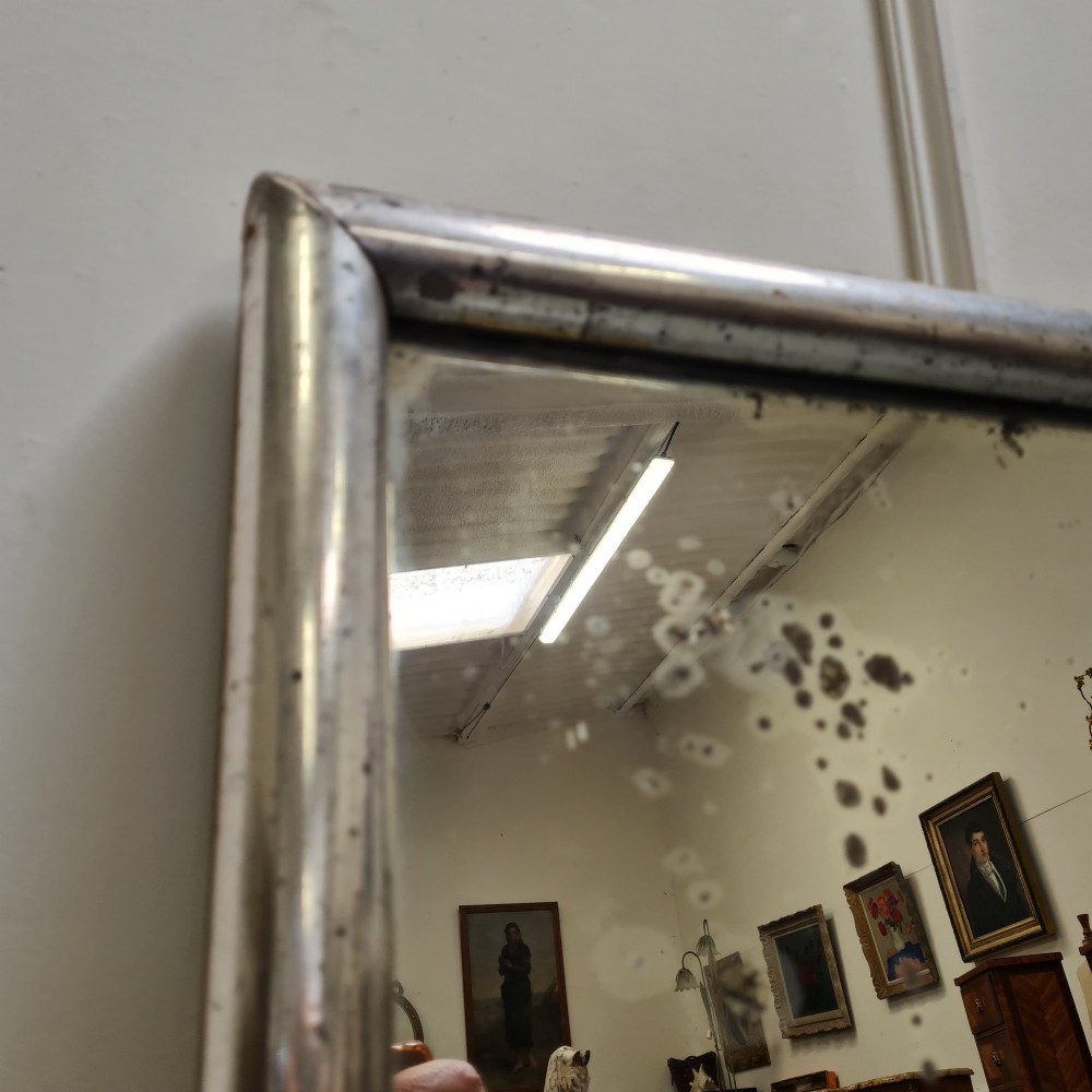 A large horizontal rectangular mirror featuring a simple moulded frame with a silver gilt finish and a reflective glass plate. View VII