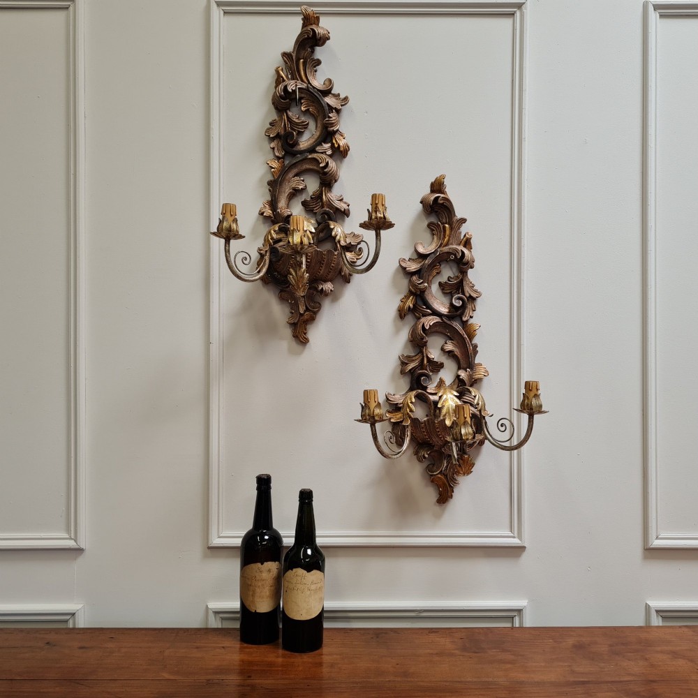 A pair of carved wooden Italian wall sconces featuring ornate acanthus leaf scrolls, gilded highlights, and three metal candle-style light branches. View II