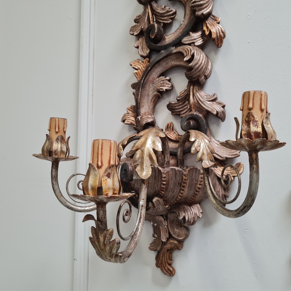 A pair of carved wooden Italian wall sconces featuring ornate acanthus leaf scrolls, gilded highlights, and three metal candle-style light branches. View III