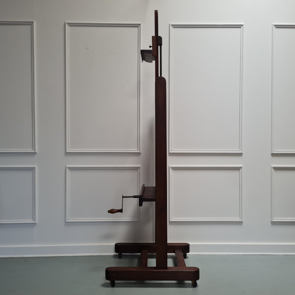 An antique dark oak studio winder easel featuring a mechanical hand crank handle and a floor base equipped with castors. View IV