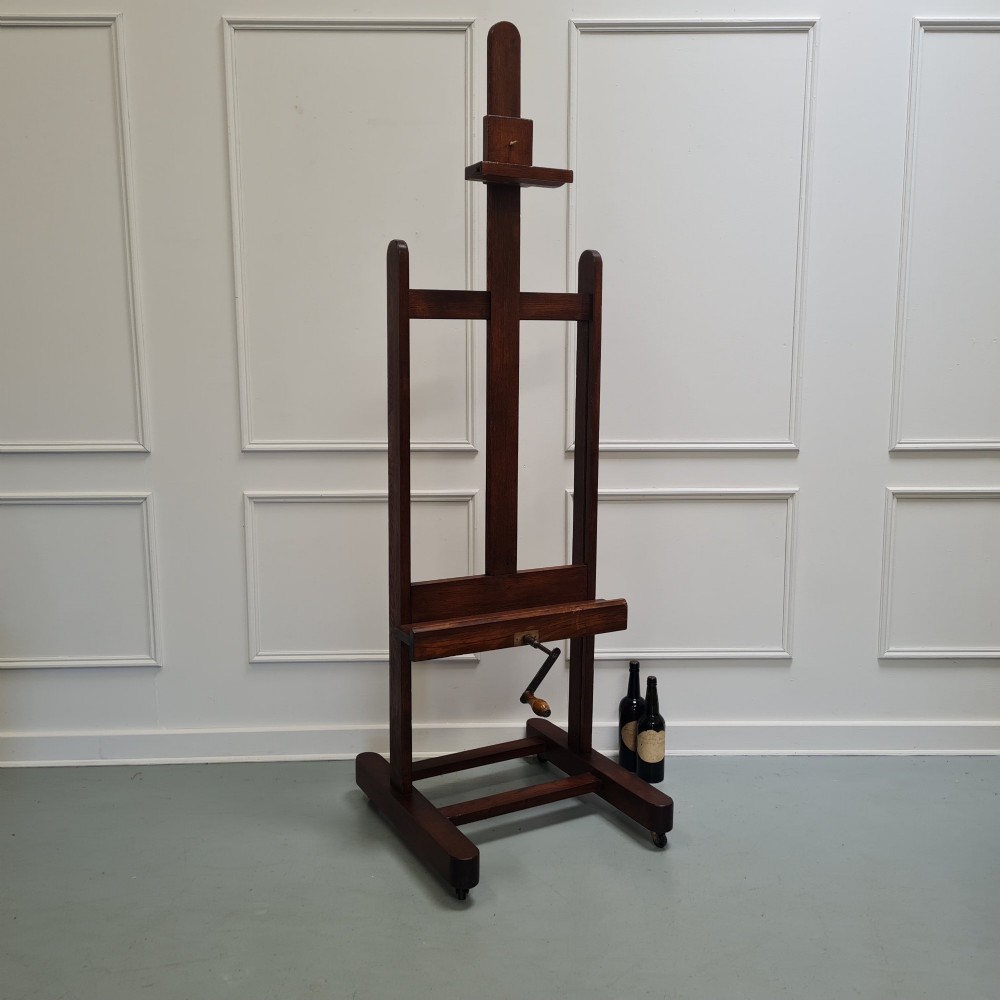 An antique dark oak studio winder easel featuring a mechanical hand crank handle and a floor base equipped with castors. View XI