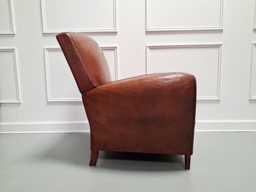 A 1930s French leather club chair upholstered in warm cognac brown patinated leather with rounded armrests and short square feet. View V