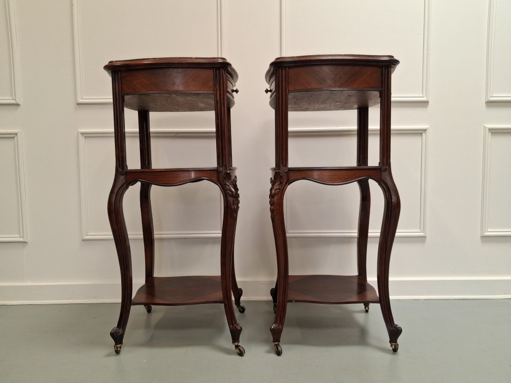 A matching pair of tall dark wood end tables featuring top drawers, lower open shelves, carved cabriole legs, and brass castors. View IV