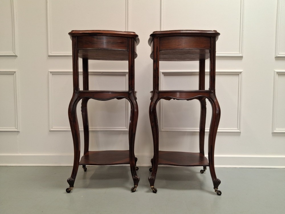 A matching pair of tall dark wood end tables featuring top drawers, lower open shelves, carved cabriole legs, and brass castors. View V