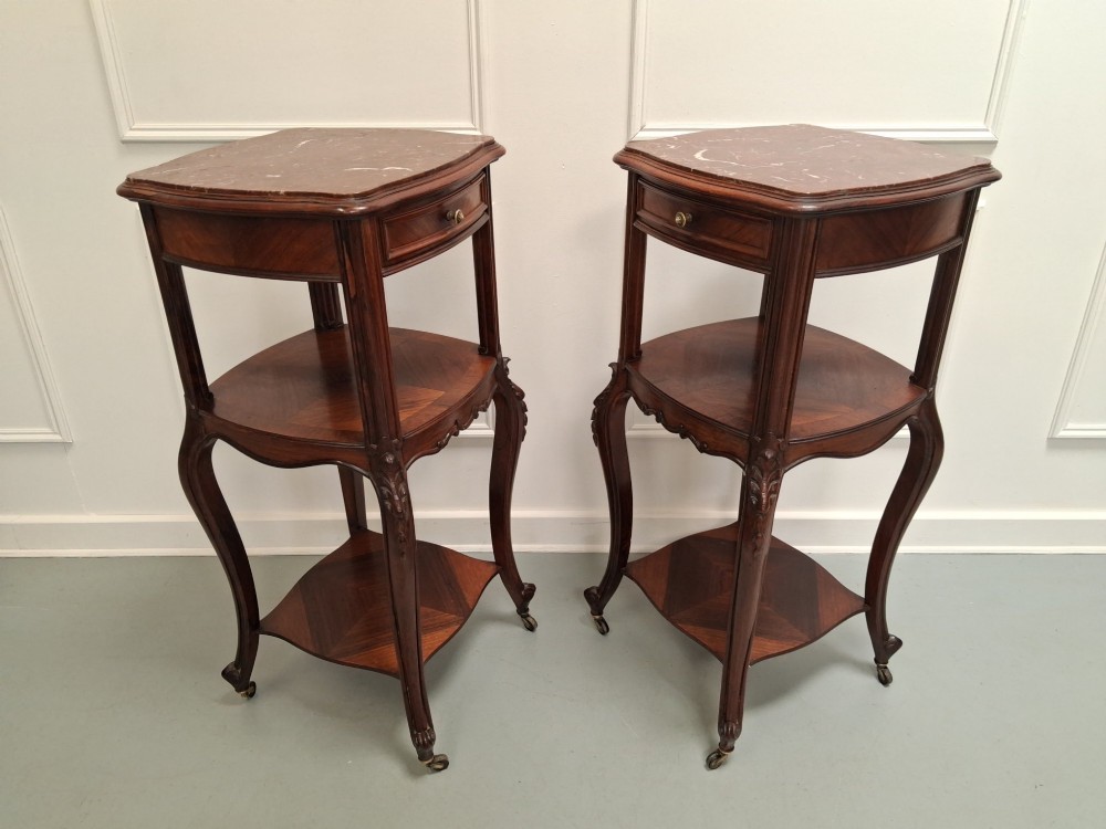 A matching pair of tall dark wood end tables featuring top drawers, lower open shelves, carved cabriole legs, and brass castors. View VI